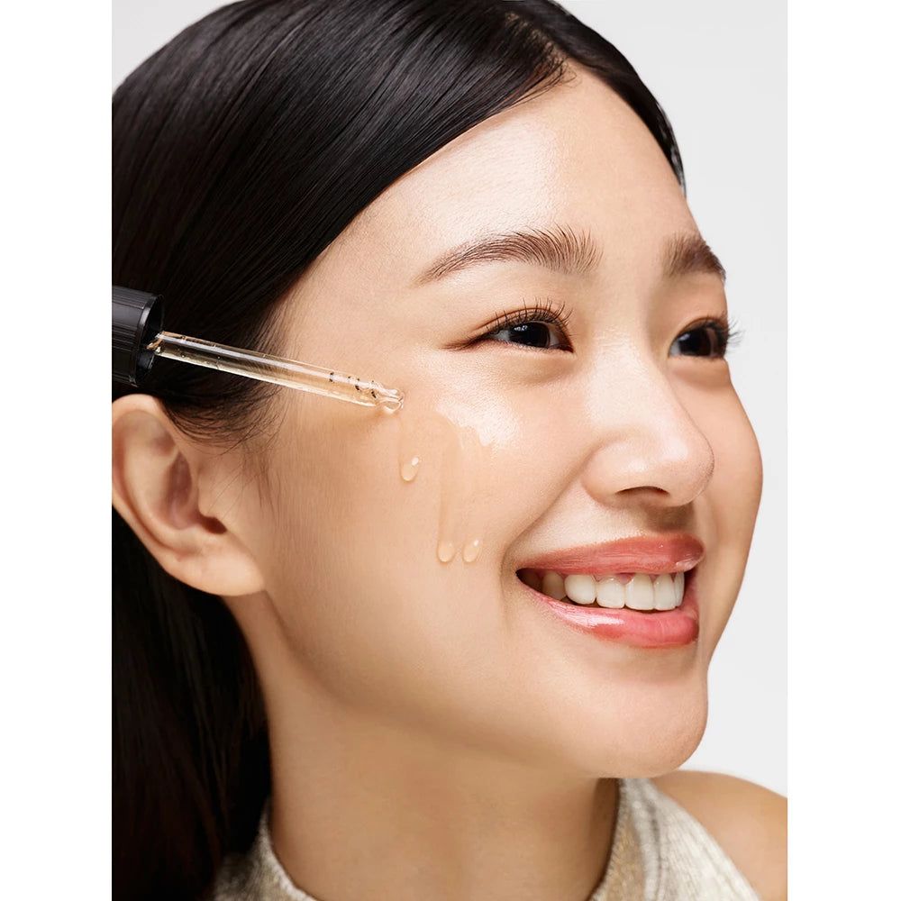 Frau mit Serum-Applikator. Serum wird auf die Haut aufgetragen. Helle Haut, dunkle Haare.