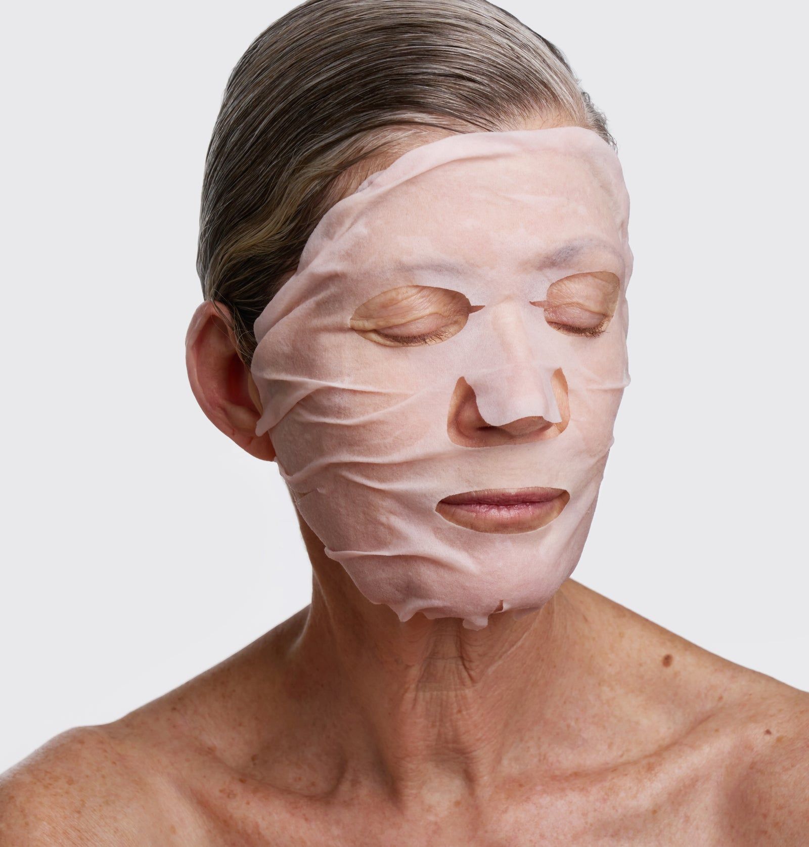 Gesichtsmaske auf Gesicht einer Frau. Maske bedeckt Augen, Nase und Mund. Rosa Farbton.