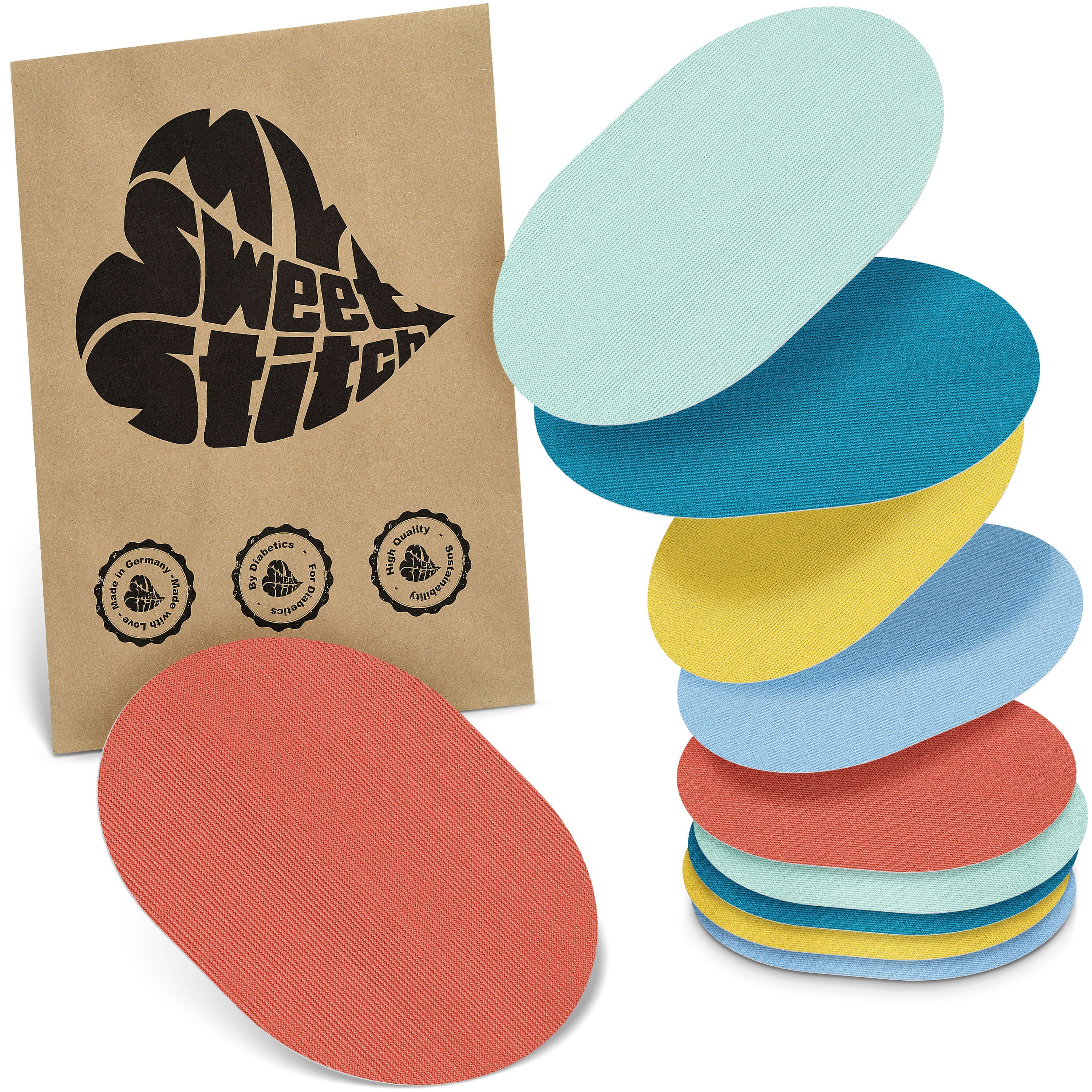 Ovale Pflaster in verschiedenen Farben. Braune Verpackung mit Logo und Qualitätssiegeln. Einzelnes Pflaster liegt davor.