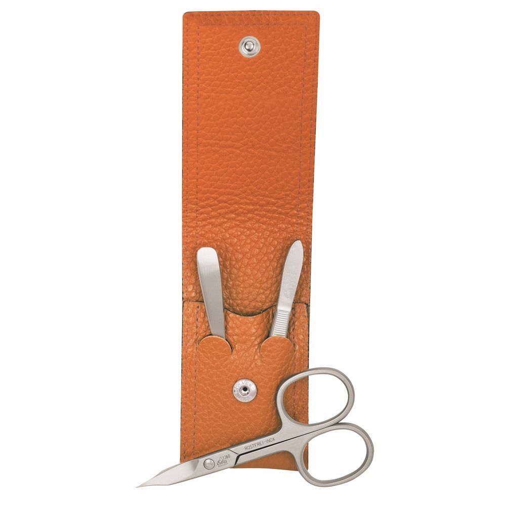 Orange Leder-Etui mit drei Maniküre-Instrumenten aus Edelstahl: Schere, Pinzette, Nagelfeile.