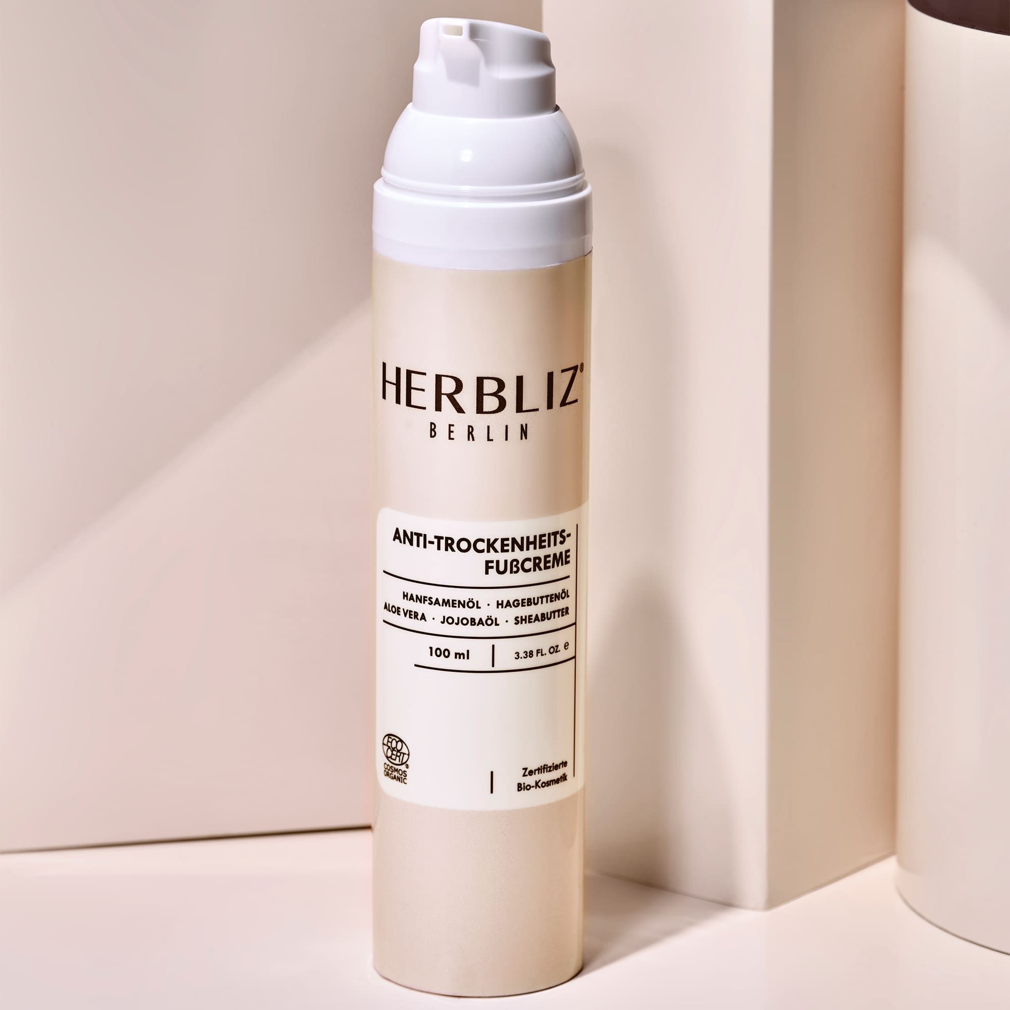 HERBLIZ Fußcreme, weiße Flasche mit Pumpverschluss. Aufschrift: Anti-Trockenheits-Fußcreme, 100 ml. Zertifizierungslogo.