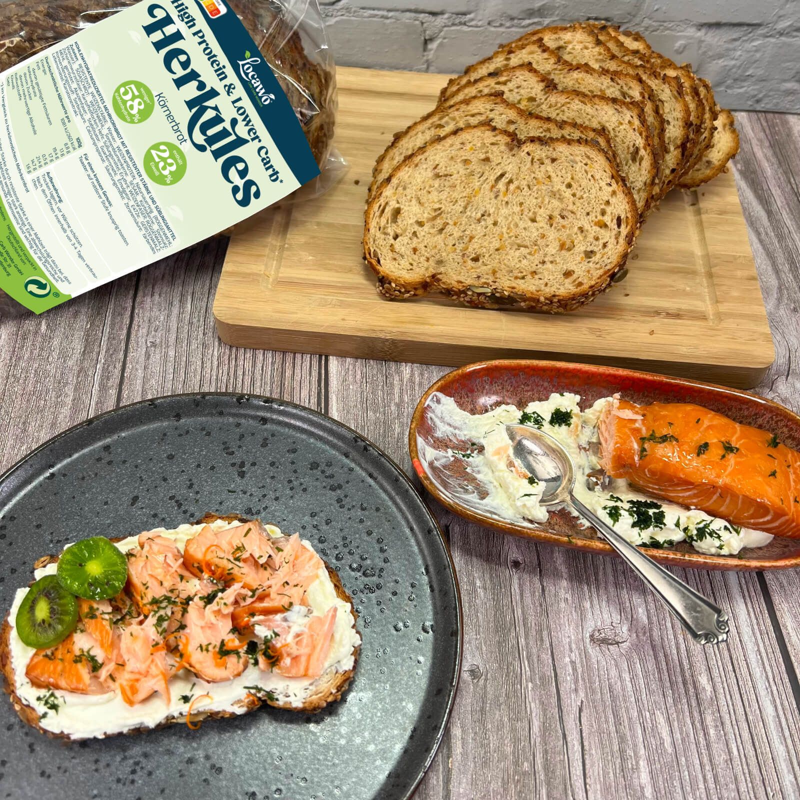 Körnerbrot Herkules und Scheiben, serviert mit Lachs und Kiwi. Verpackung im Hintergrund.