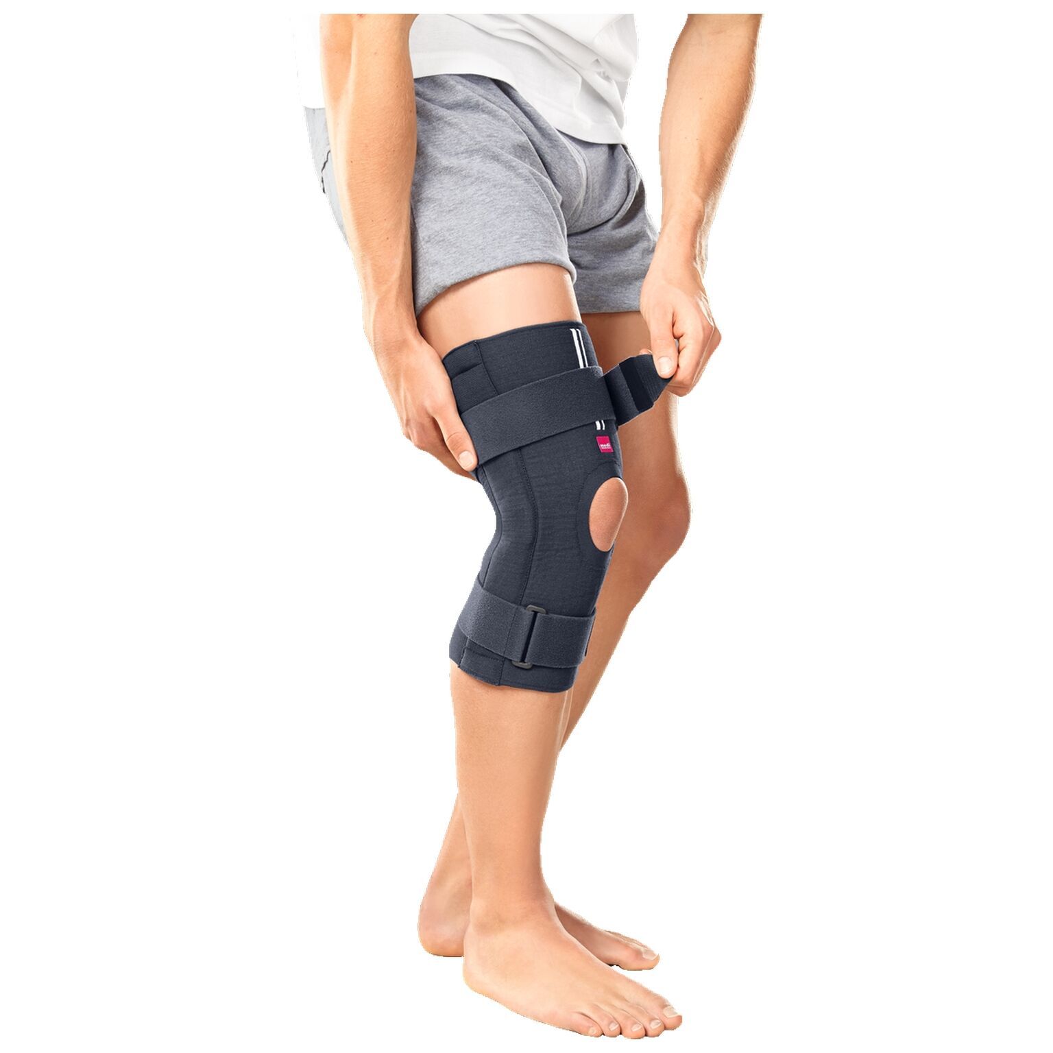 Person trägt Knieorthese. Dunkelgrau, mit Knieöffnung und Klettverschlüssen. Marke medi.