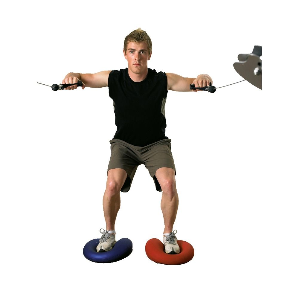 Mann trainiert mit zwei Ballkissen. Ein blaues und ein rotes Kissen unter den Füßen. Der Mann hält zwei Griffe.