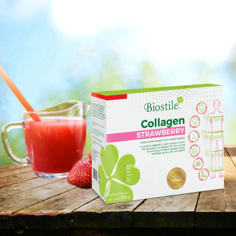 Glas Erdbeergetränk mit Strohhalm auf Holztisch. Daneben Packung Biostile Collagen Strawberry und Erdbeere.