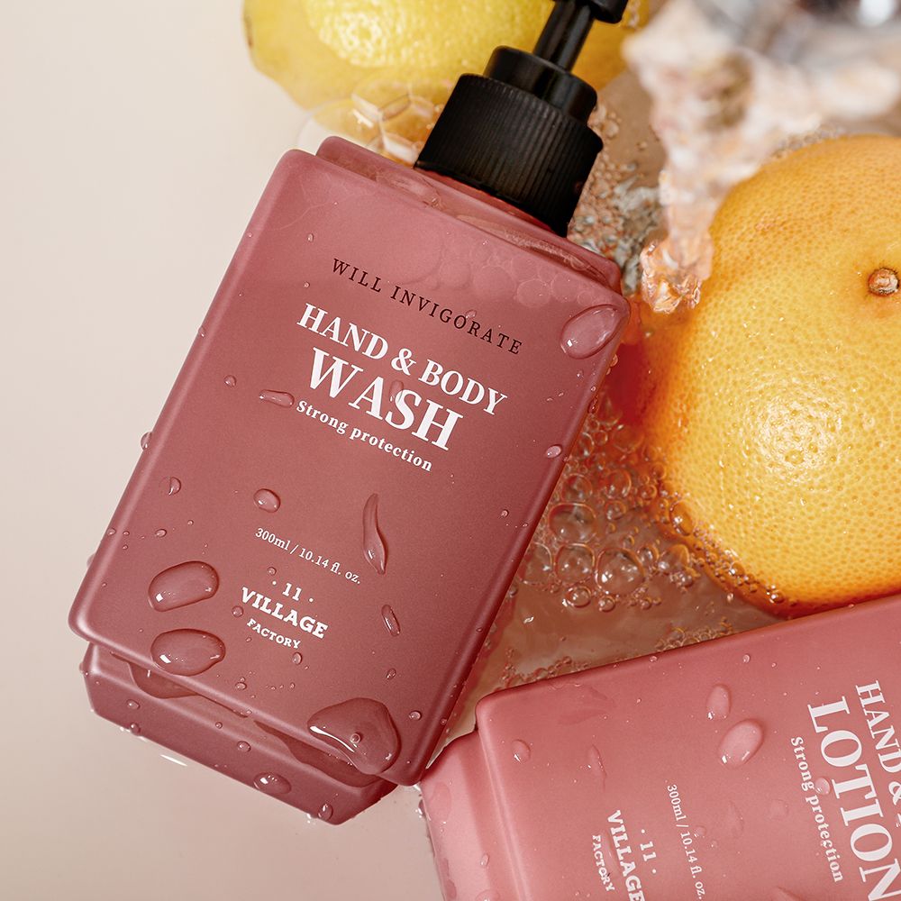 Rosa Hand- und Körperwaschmittel-Flaschen mit schwarzem Spender. Aufschrift: Hand & Body Wash, Strong protection, 11 Village Factory. Wasser-Effekt.