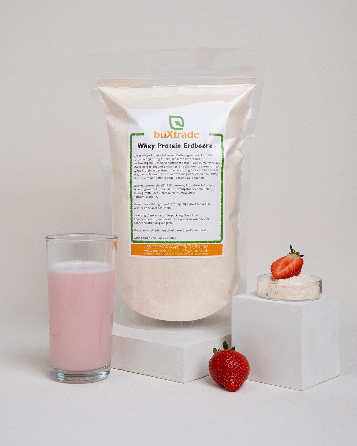 Verpackung von buXtrade Whey Protein Erdbeere, Glas mit rosa Flüssigkeit, Erdbeeren.