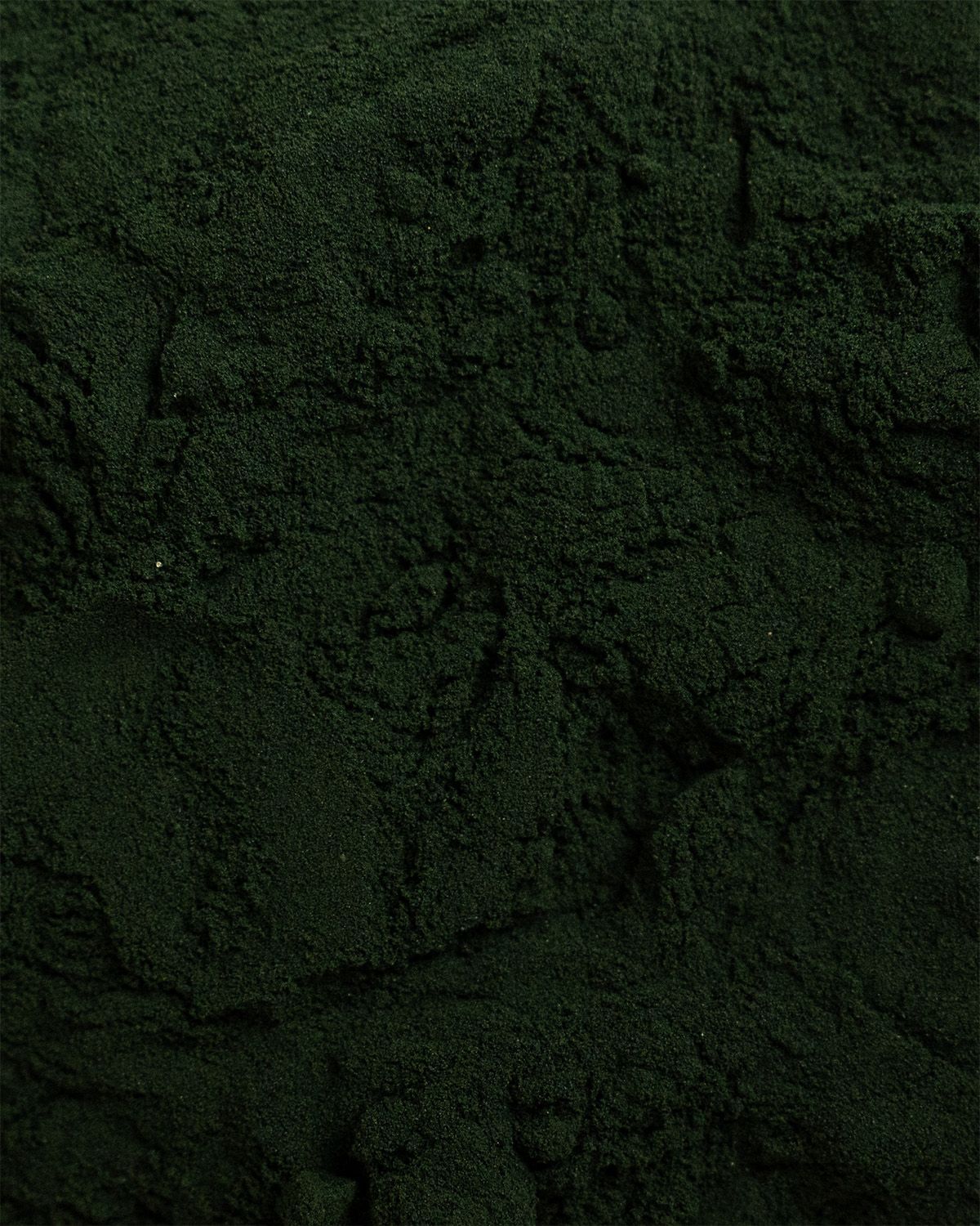 Nahaufnahme von Spirulina-Pulver. Dunkelgrüne, feine Textur.