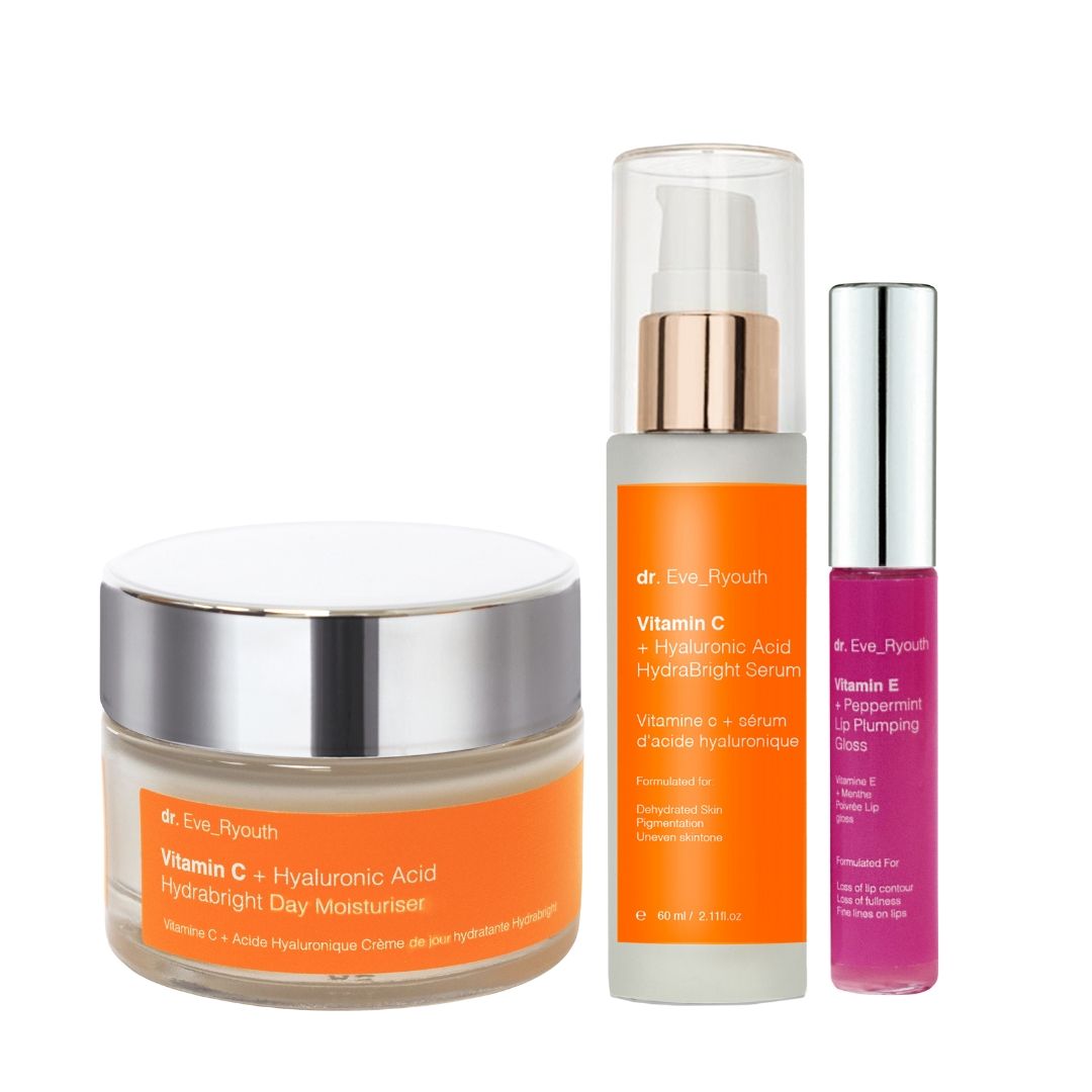 Drei Kosmetikprodukte: Creme, Serum und Lipgloss. Creme- und Serumbehälter mit orangefarbenen Etiketten. Lipgloss in pinkfarbener Hülle.