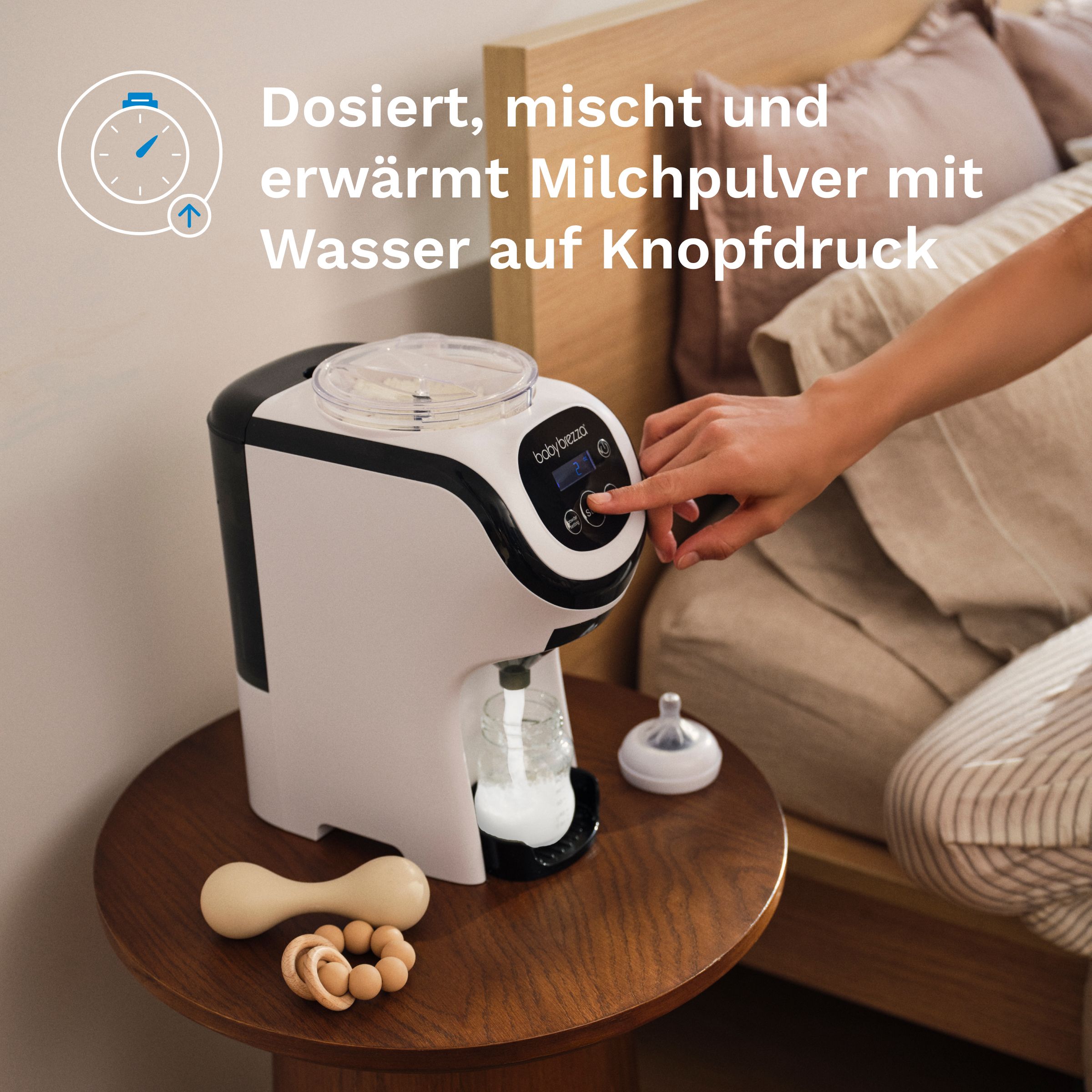 Baby Brezza Milchzubereiter in weiß und schwarz, daneben eine Hand, die einen Knopf drückt.