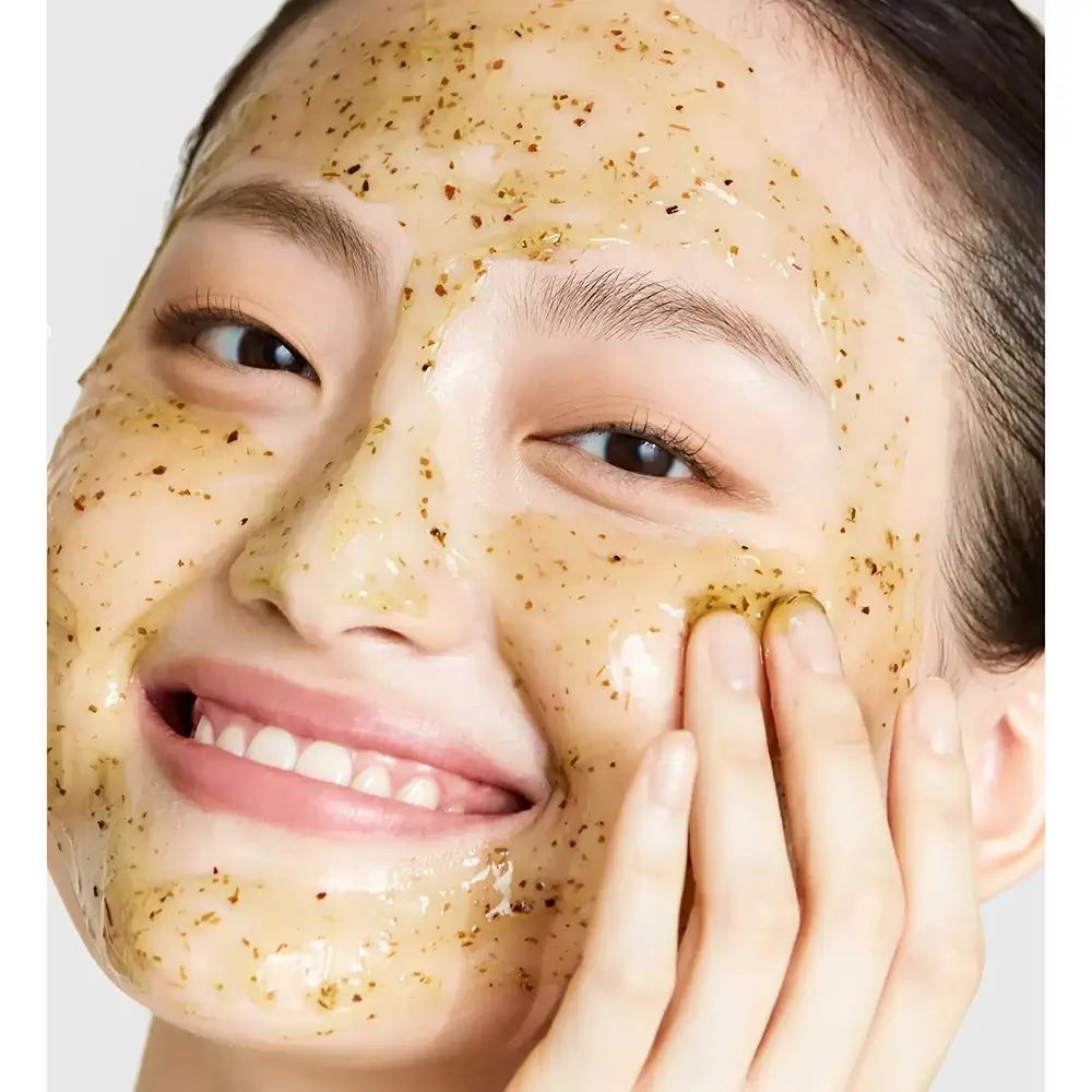 Gesicht einer Frau mit Gesichtsmaske. Die Maske ist gelb und enthält kleine Partikel.