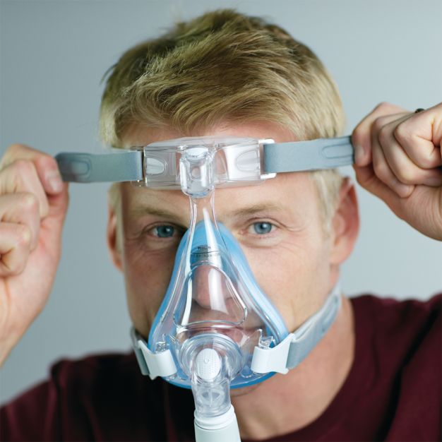 Mann mit Philips CPAP Maske Amara SE Gel Full: Kopfband wird angepasst.