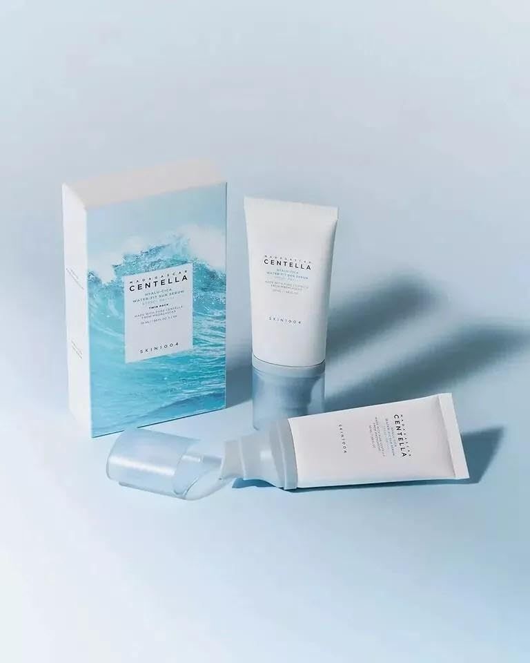 Zwei Tuben und eine Schachtel. Aufschrift: Centella Hyalu-Cica Water-Fit Sun Serum. Marke: SKIN1004. Blaue und weiße Verpackung.