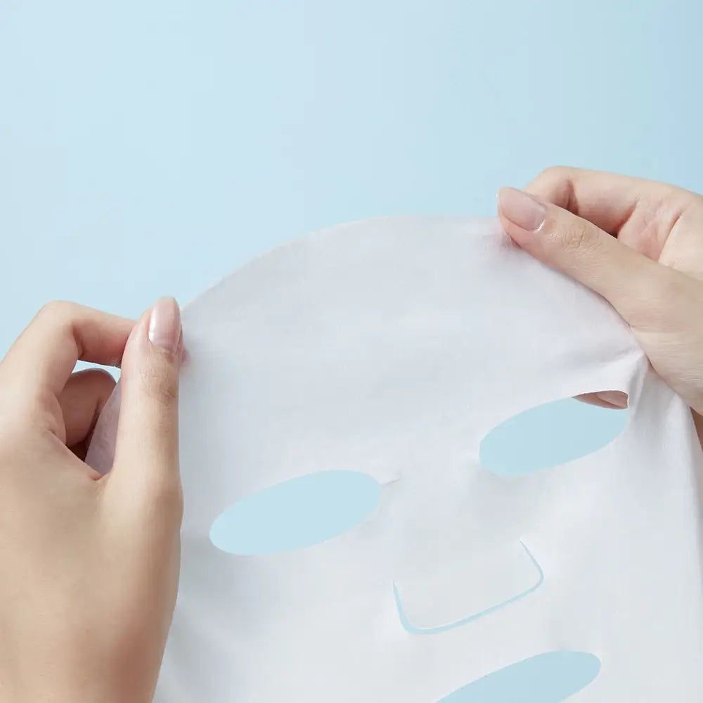 Gesichtsmaske mit Aussparungen für Augen, Nase und Mund. Hände halten die weiße Maske vor blauem Hintergrund.