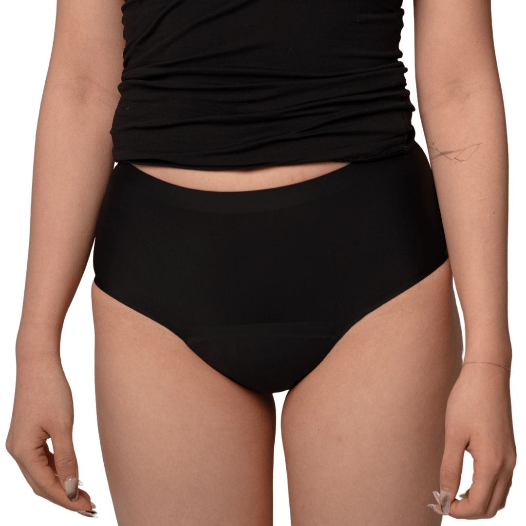 Schwarzer, hoher Slip. Die Unterwäsche bedeckt den Bauch und die Oberschenkel. Die Person trägt ein schwarzes Tanktop.