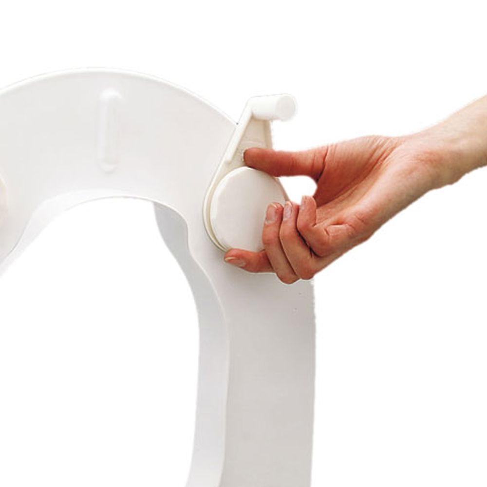 Weißes Befestigungselement mit rundem Drehknopf. Eine Hand betätigt den Knopf. Teil eines Toilettensitzes.