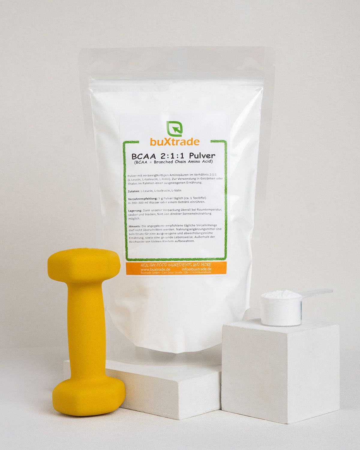 buXtrade BCAA 2:1:1 Pulver in weißer Standbodenbeutel-Verpackung, mit Messlöffel und gelbem Hantel.