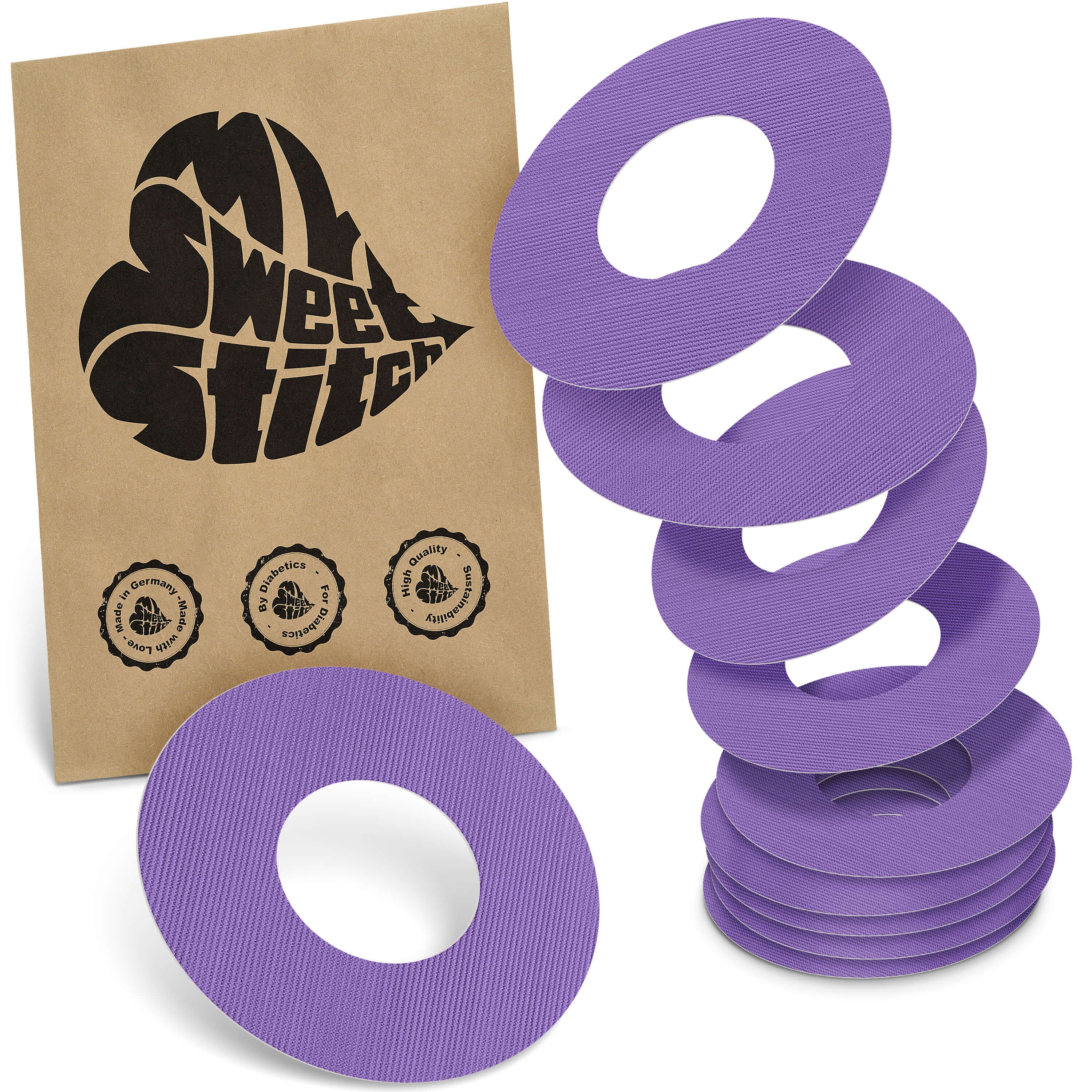 Fixierringe, lila, mit Loch. Sechs Ringe gestapelt, einer liegt. Braune Verpackung mit Logo 'MySweetStitch' und Siegeln.