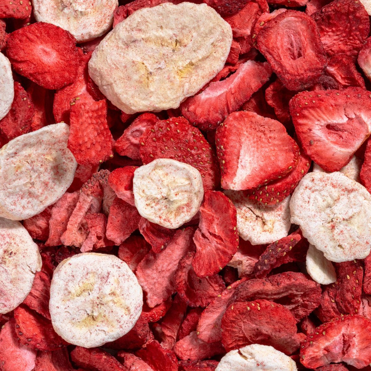 Nahaufnahme von gefriergetrockneten Erdbeer- und Bananenscheiben. Rote Erdbeeren und helle Bananenstücke.