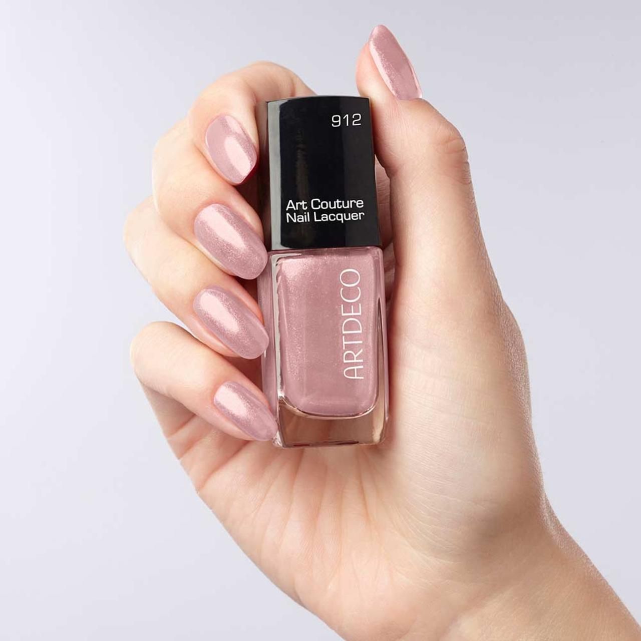 Hand hält Nagellackflasche. Rosa Lack. Aufschrift: Artdeco Art Couture Nail Lacquer. Nägel lackiert.