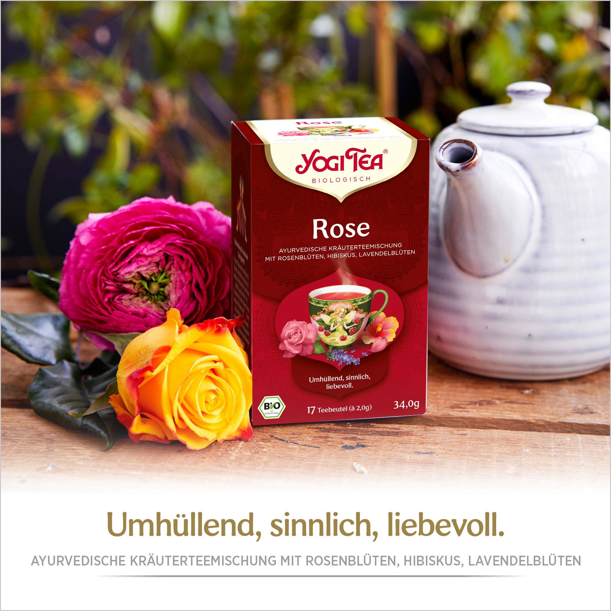 Yogi Tea Rose Bio Kräutertee Packung. Rote Verpackung, Logo, Produktname. Neben Rosen und Teekanne. 17 Teebeutel.