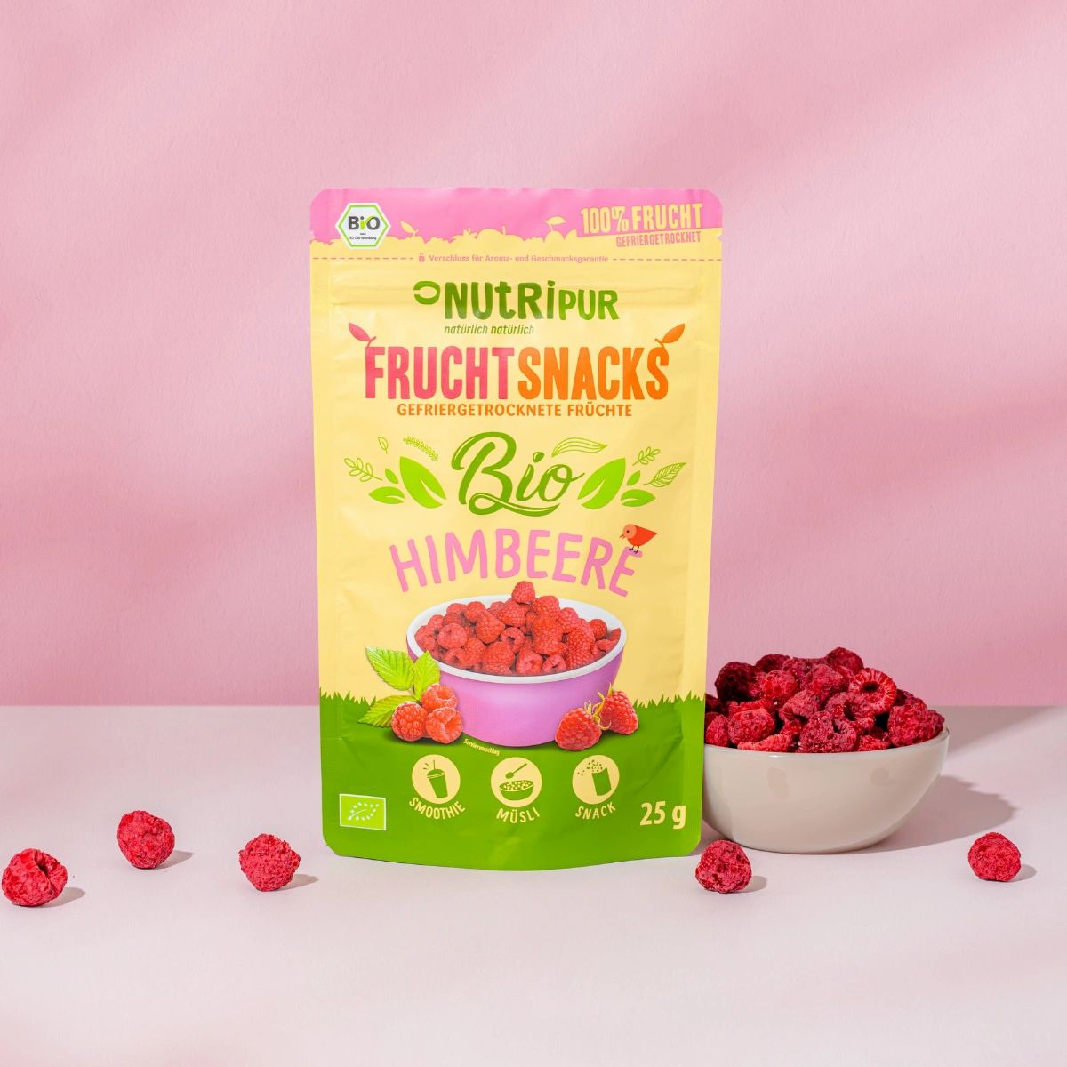 Beutel mit gefriergetrockneten Bio-Himbeeren, Schale mit Himbeeren, Himbeeren verstreut.