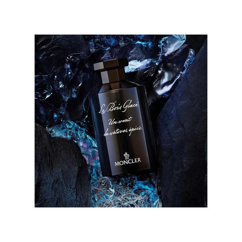 Dunkelbraune Flasche. Aufschrift: Le Bois Glacé, Un vent de vétiver épicé, MONCLER. Hintergrund: blaue und schwarze Elemente.