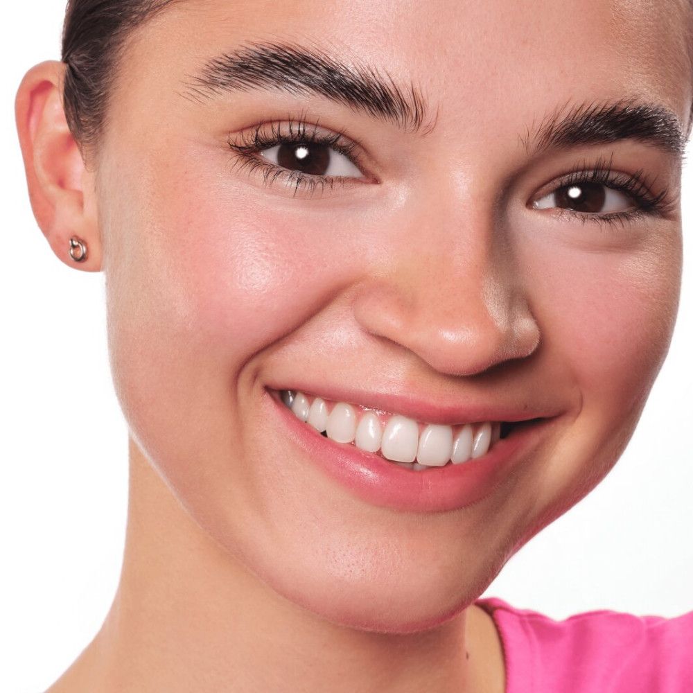 Nahaufnahme eines lächelnden Gesichts. Hautton, Augenbrauen, Augen, Zähne. Trägt Ohrringe.