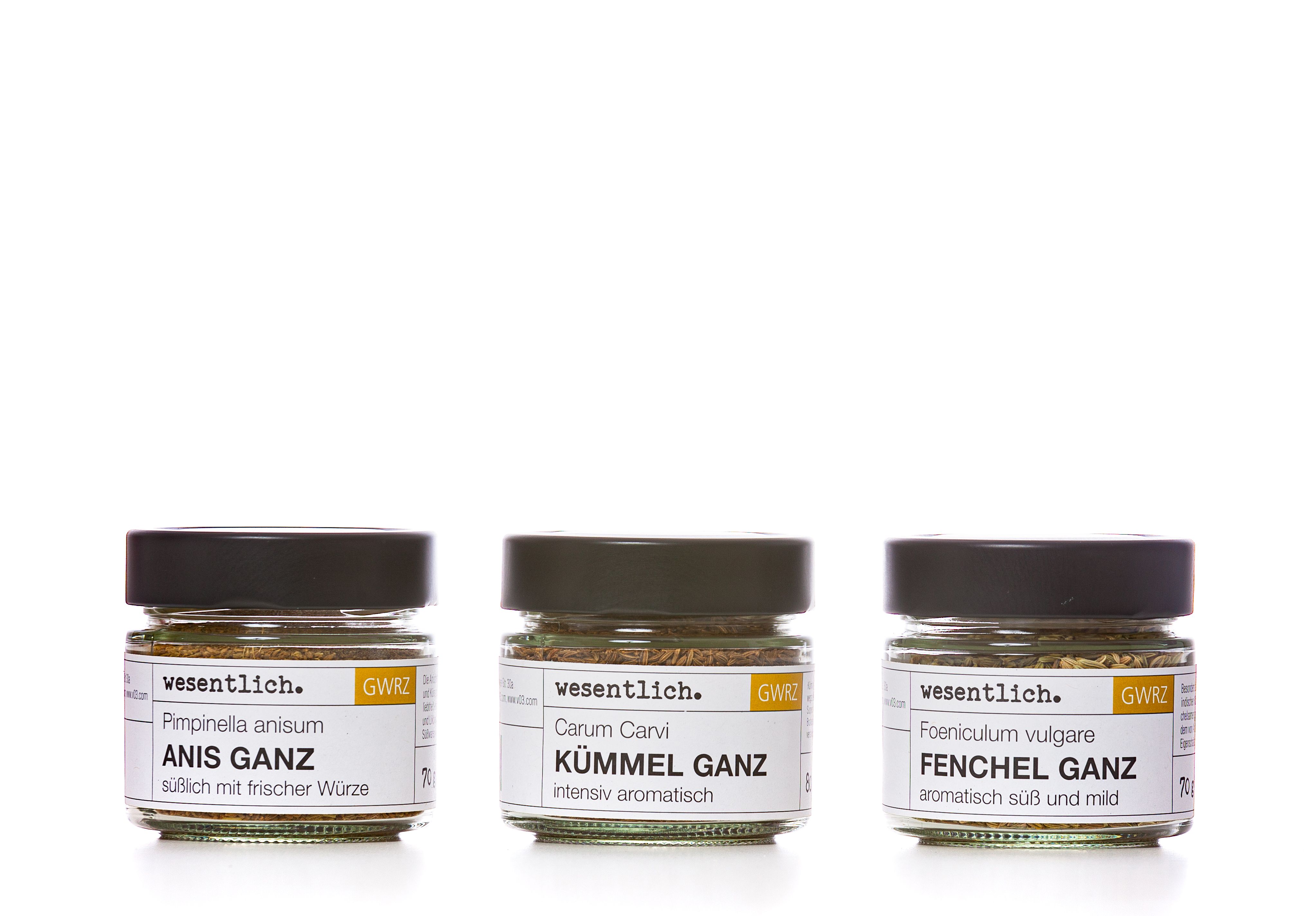 Drei Gewürzgläser nebeneinander. Etiketten: Anis, Fenchel, Kümmel. Marke: wesentlich. Gewürze sind sichtbar.