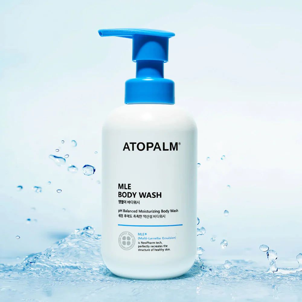 Weiße Flasche mit blauem Pumpkopf. Aufschrift: ATOPALM MLE Body Wash. Wasserhintergrund.