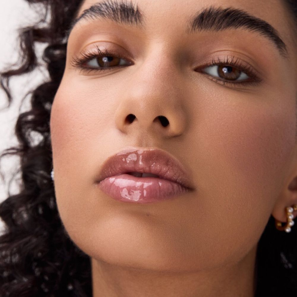 Nahaufnahme eines Gesichts mit glänzenden Lippen. Lip Elixir auf den Lippen.