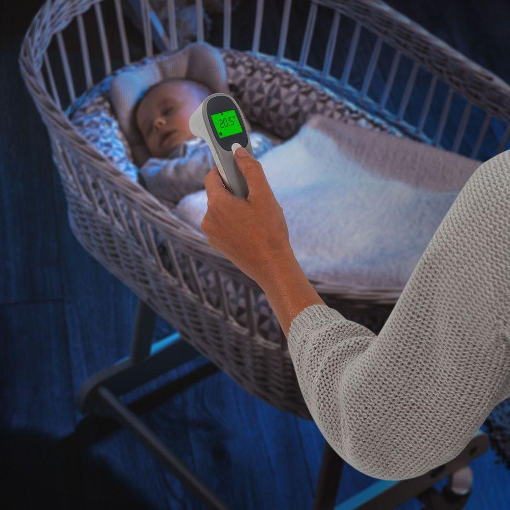 Infrarot-Thermometer misst die Temperatur eines schlafenden Babys. Das Display zeigt 36,5°C.