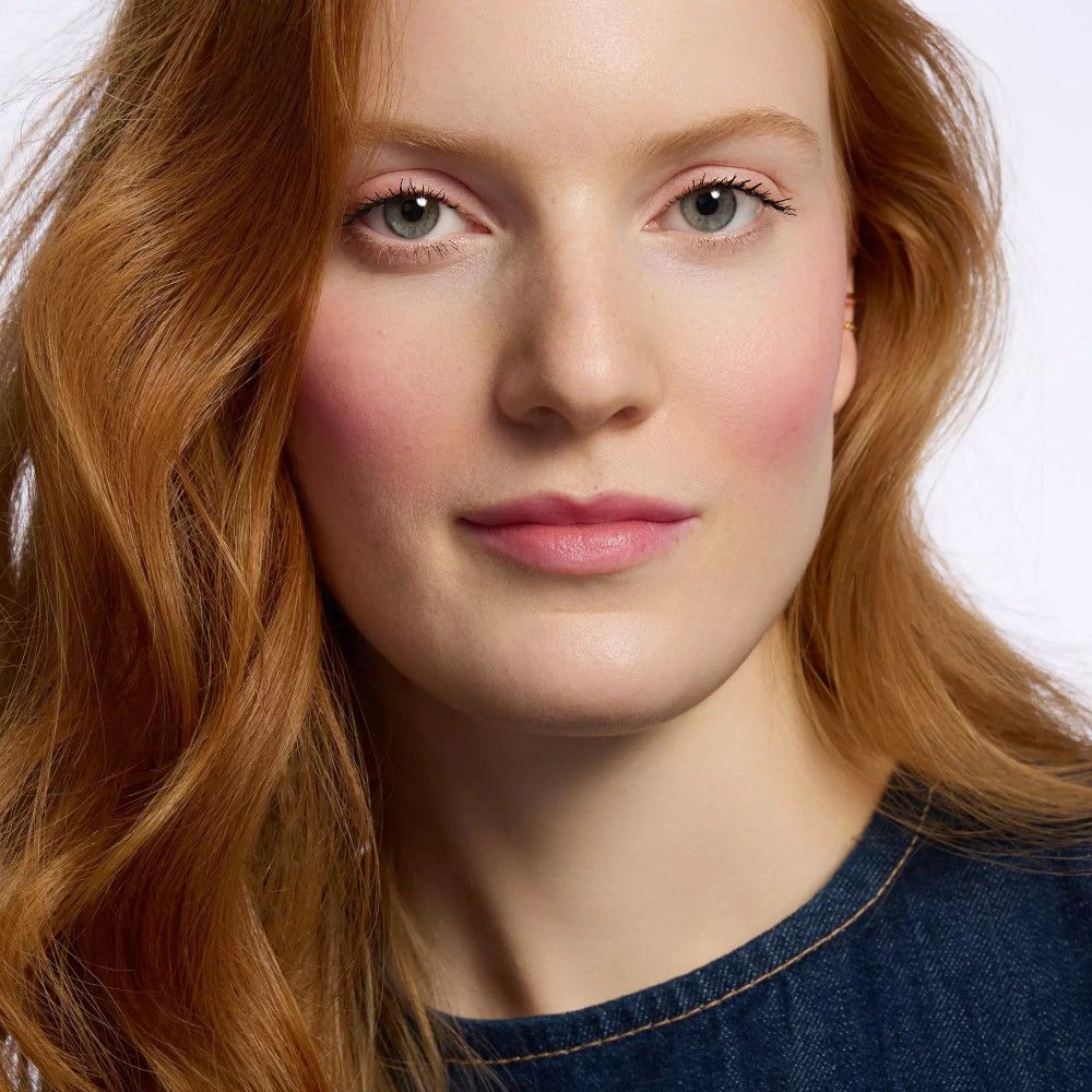 Porträt einer Frau mit roten Haaren und blauen Augen. Sie trägt ein Jeanshemd.