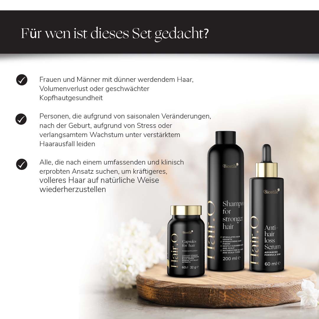 Biostile Hair.O Set: Shampoo, Serum und Kapseln auf einem Holzpodest, umgeben von grünen Blättern.