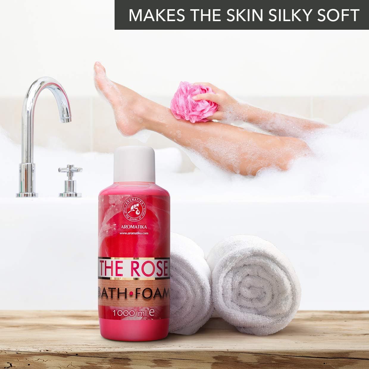 Rosa Flasche AROMATIKA THE ROSE BATH FOAM neben Badewanne. Frau mit Schaum und Handtuch. Wasserhahn im Hintergrund.