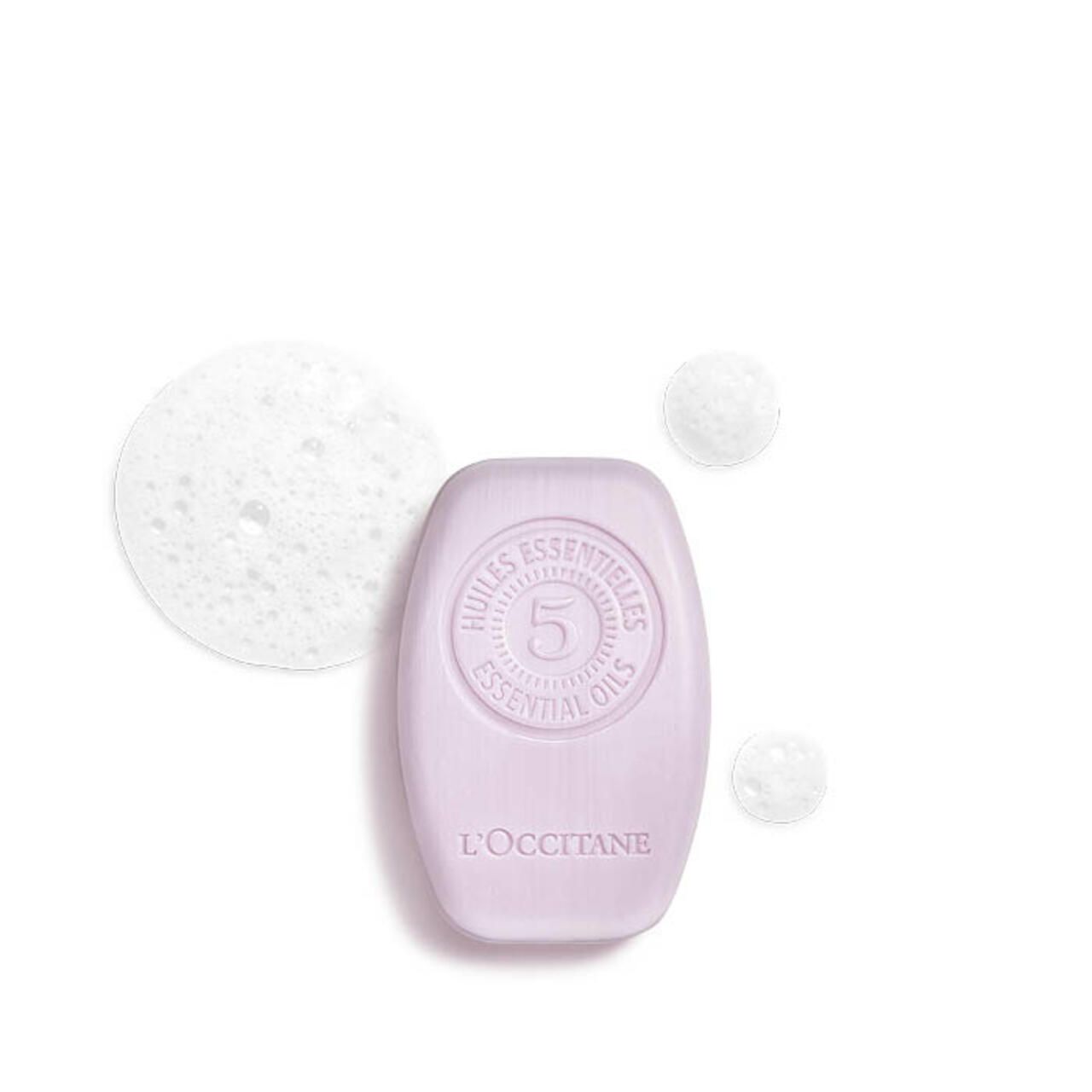 Ovales, helllila festes Shampoo mit Prägung. L'Occitane-Logo unten. 5 Essential Oils-Siegel oben. Schaumblasen.