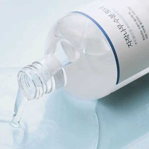 Produkt, transparente Flasche mit Flüssigkeit, die ausgegossen wird. Aufschrift in koreanischer Schrift.