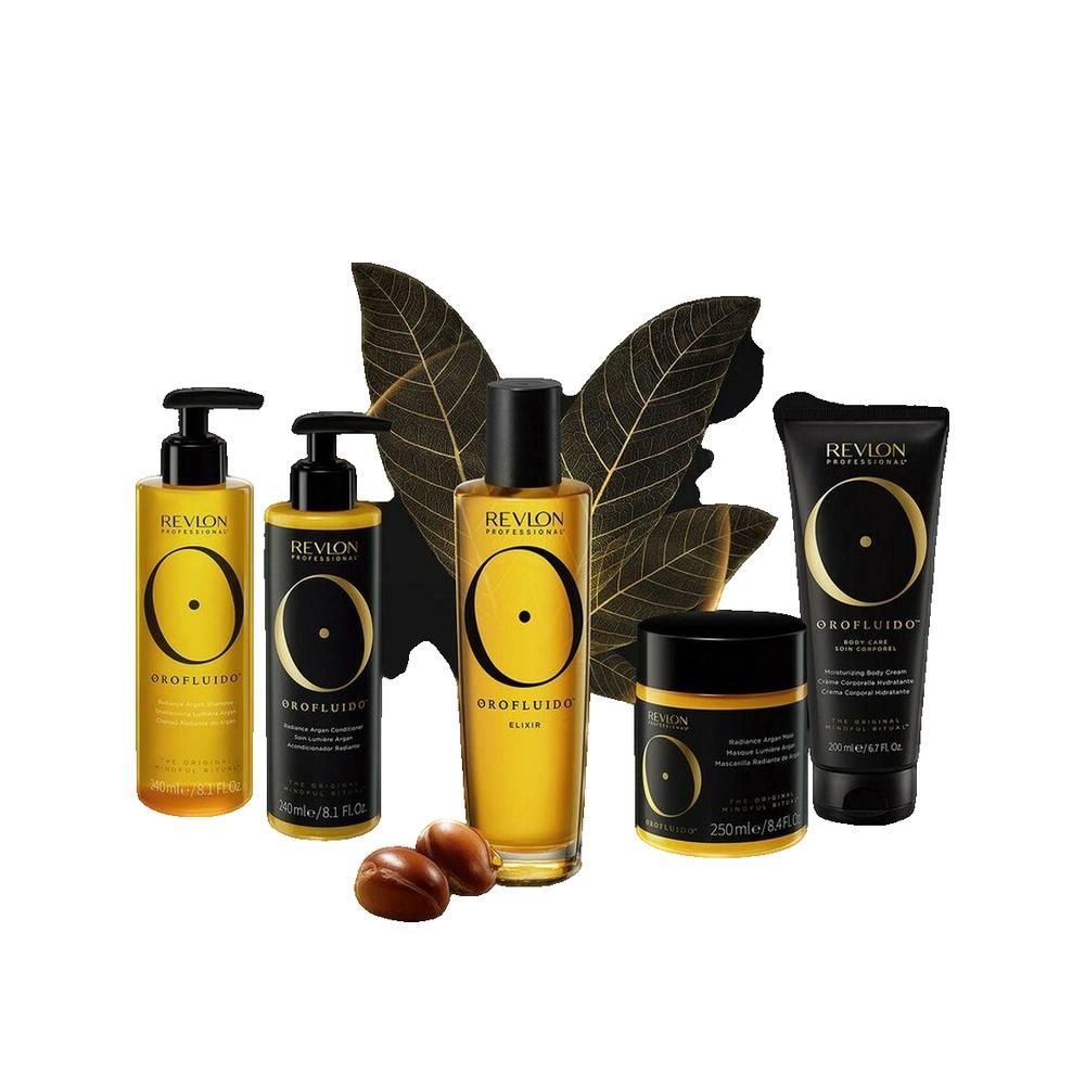 Verschiedene Orofluido-Produkte. Flaschen, Tiegel und Tube in Gold und Schwarz. Argan-Samen liegen daneben.