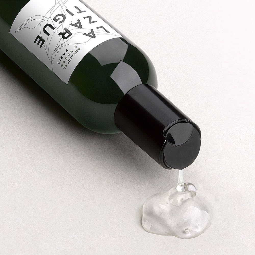 Grüne Flasche, schwarzer Deckel. Flüssigkeit tropft heraus. Aufschrift: La Zarzatique, Botanisch & Vegan.