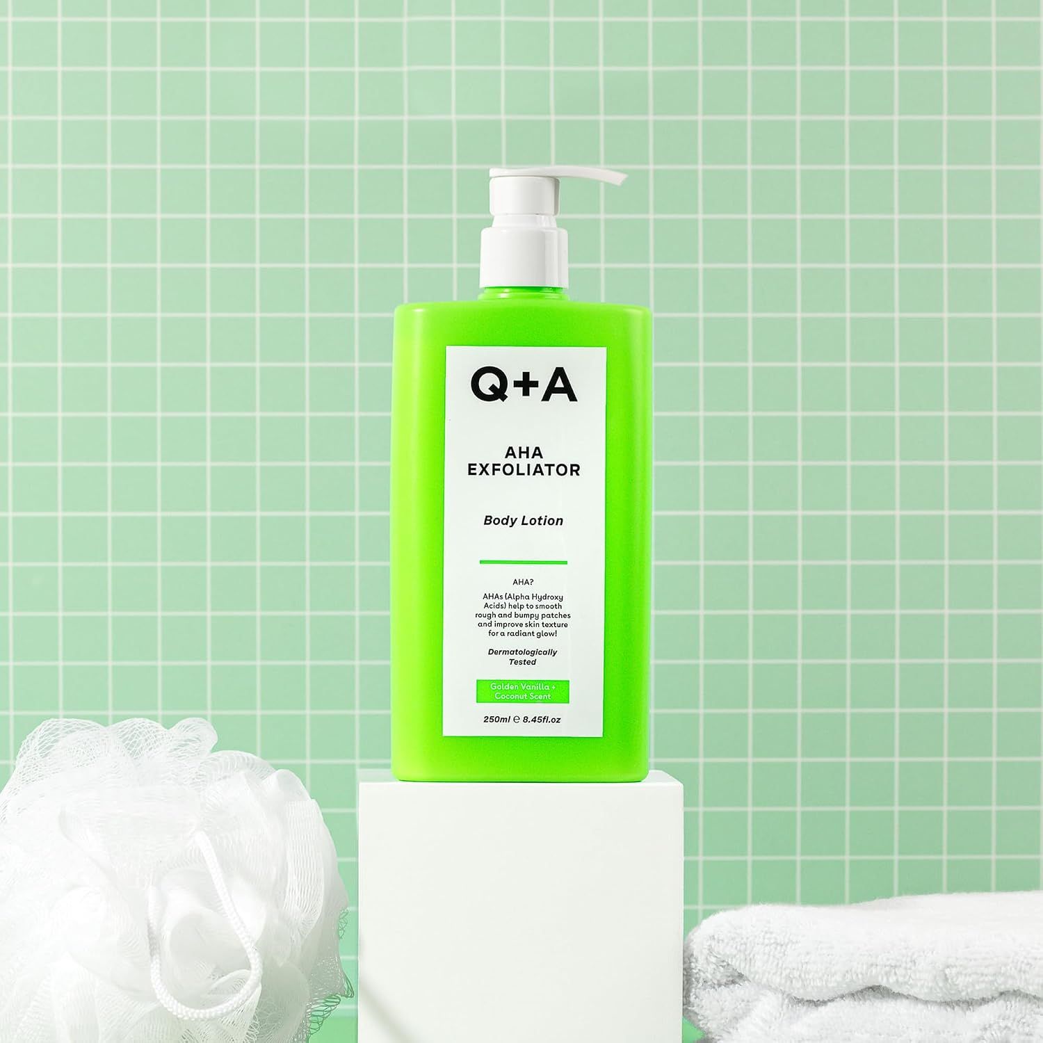 Grüner Spender Q+A AHA Exfoliator Body Lotion auf einem Podest.
