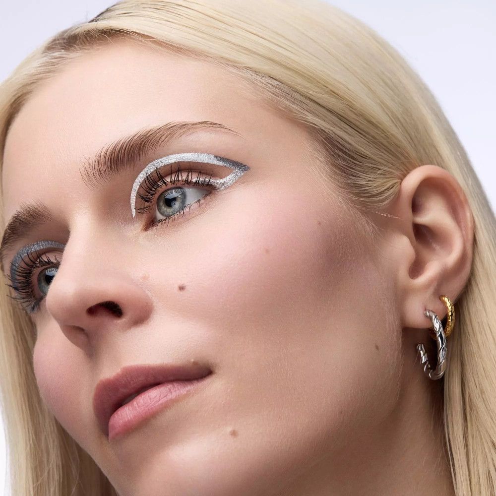 Porträt einer Frau mit blonden Haaren und blauem Augen-Make-up. Silberner Eyeliner-Strich am oberen Lid.