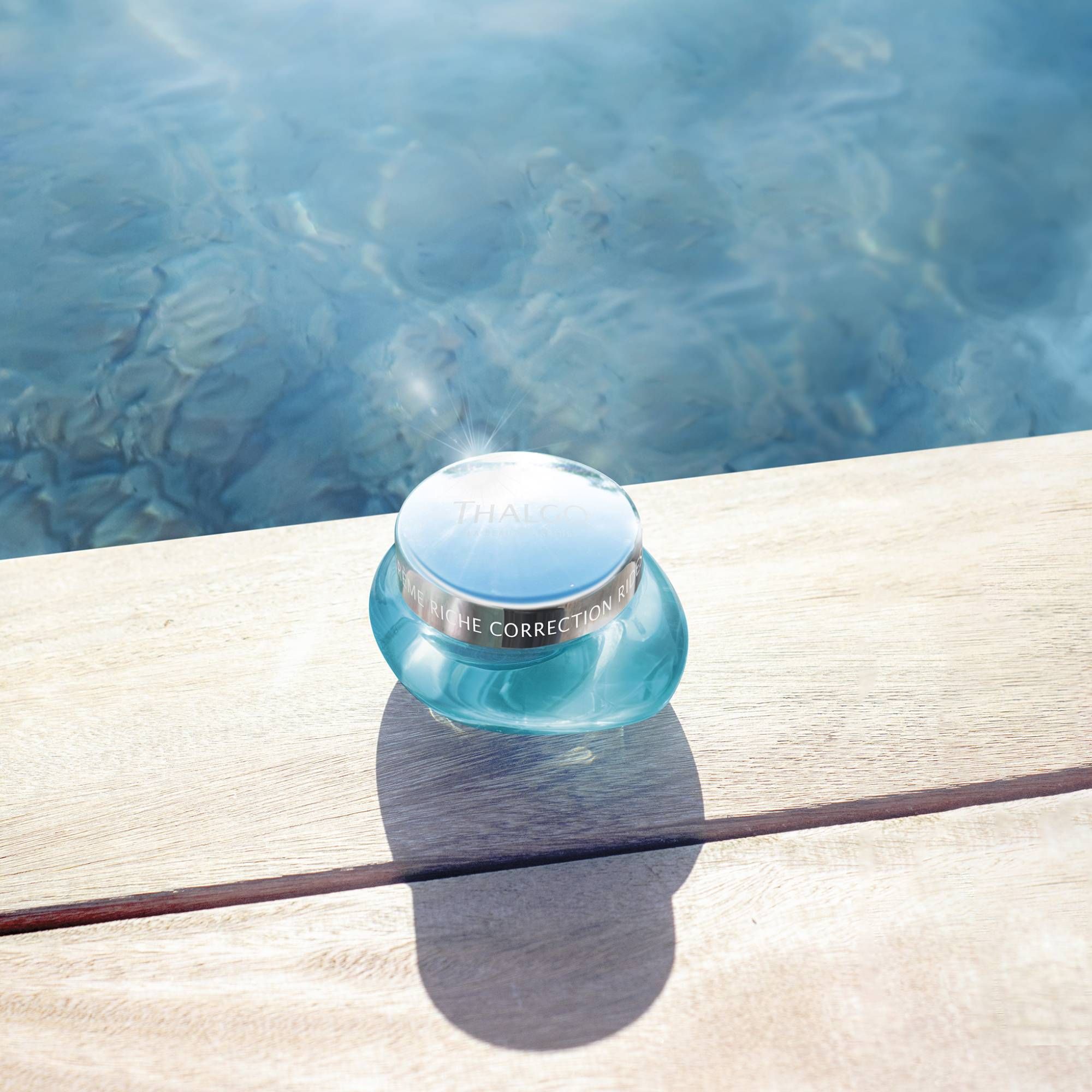 Türkisfarbener Tiegel auf Holzoberfläche. Silberner Deckel mit Aufschrift. Schattenwurf.