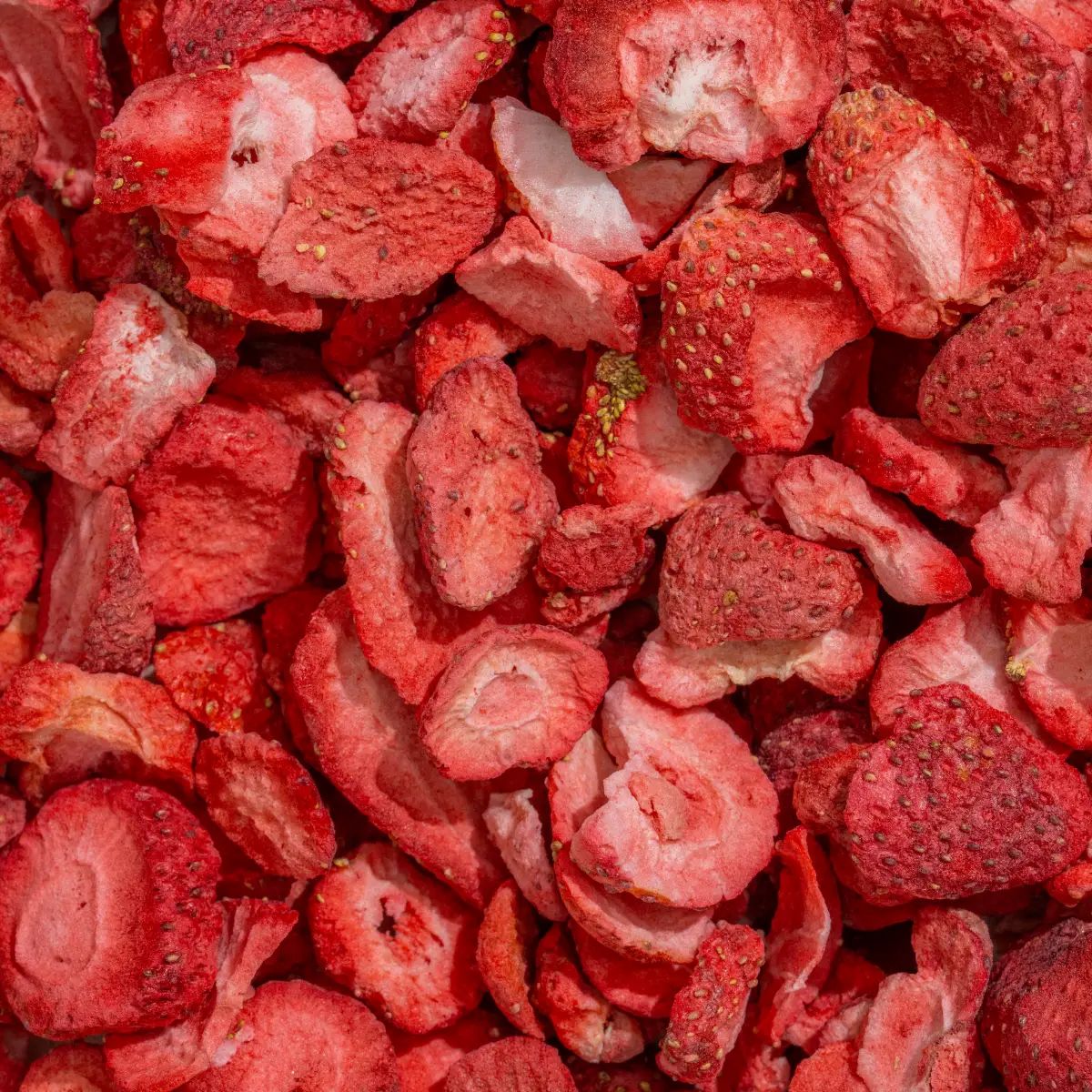 Nahaufnahme von gefriergetrockneten Erdbeerstücken. Rote, getrocknete Erdbeeren, geschnitten in verschiedenen Formen und Größen.