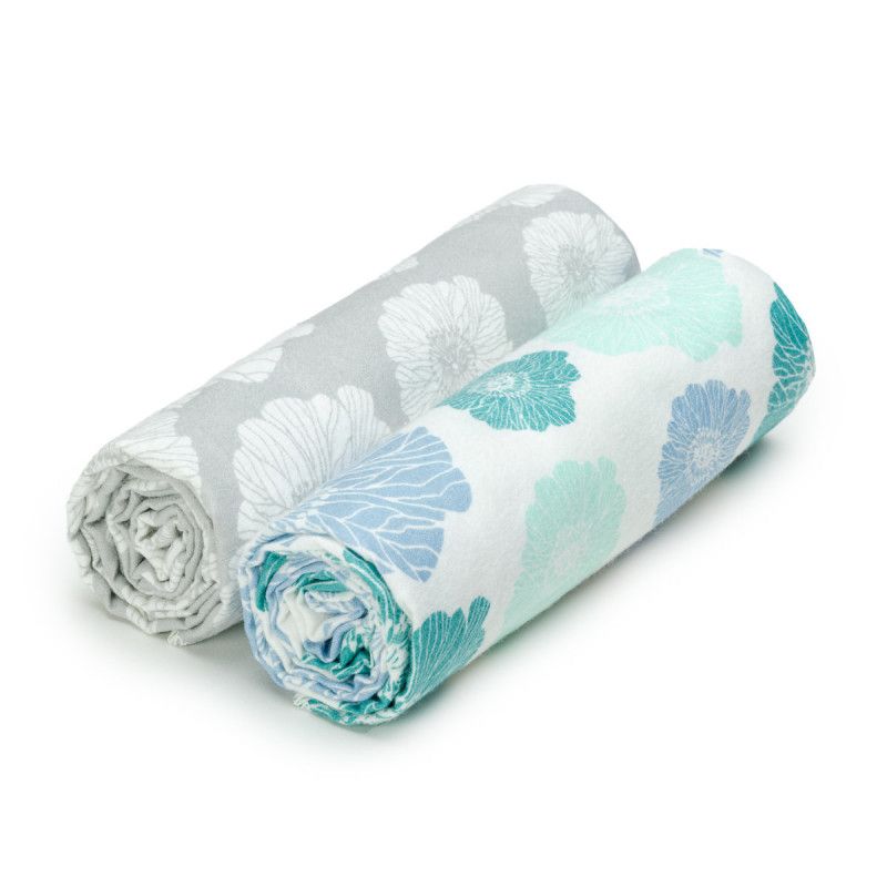 Zwei gerollte Stoffbadetücher mit floralem Muster. Farben: Grau, Türkis, Blau und Weiß. Baumwolle.