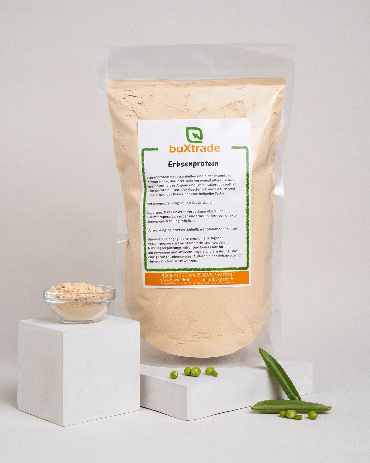 Beutel buXtrade Erbsenprotein-Pulver. Kleiner Behälter mit Pulver, Erbsen und Schoten. Auf weißem Podest.