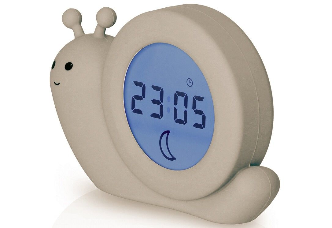 Beigefarbener Schlaftrainer in Schneckenform. Digitalanzeige mit Uhrzeit und Mondsymbol. Die Uhr zeigt 23:05 an.