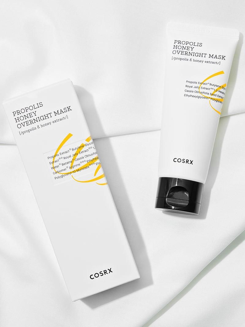 Weiße Tube mit schwarzem Deckel und Karton. Aufschrift: PROPOLIS HONEY OVERNIGHT MASK. Marke: COSRX. Auf weißem Hintergrund.