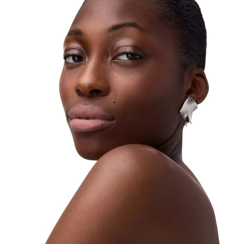 Porträt einer Frau mit Nude-Lippen. Sie trägt silberne Ohrringe.