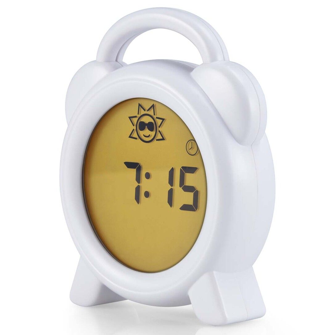 Wecker mit weißem Gehäuse, gelbem Display. Zeigt 7:15 Uhr an. Sonnensymbol. Griff oben.