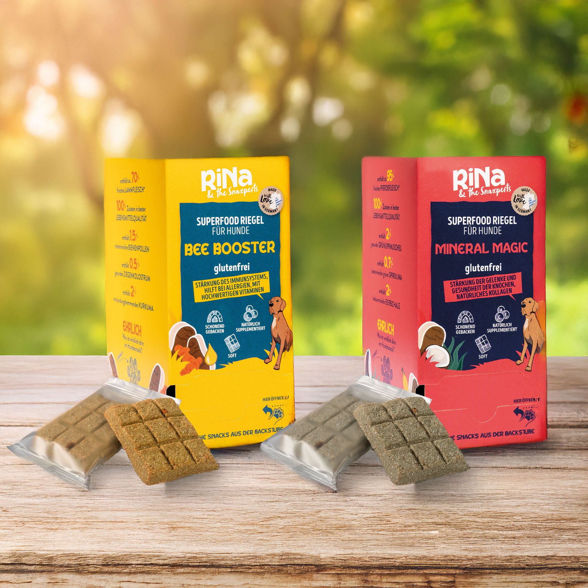 Zwei Verpackungen mit Hundesnacks. Aufschrift: BEE BOOSTER und MINERAL MAGIC, glutenfrei. Daneben jeweils ein Snack.
